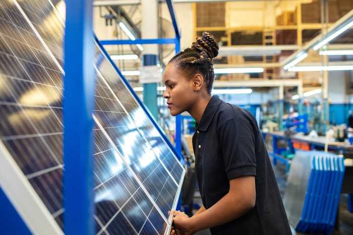 A woman working on a solar panel in a factory.